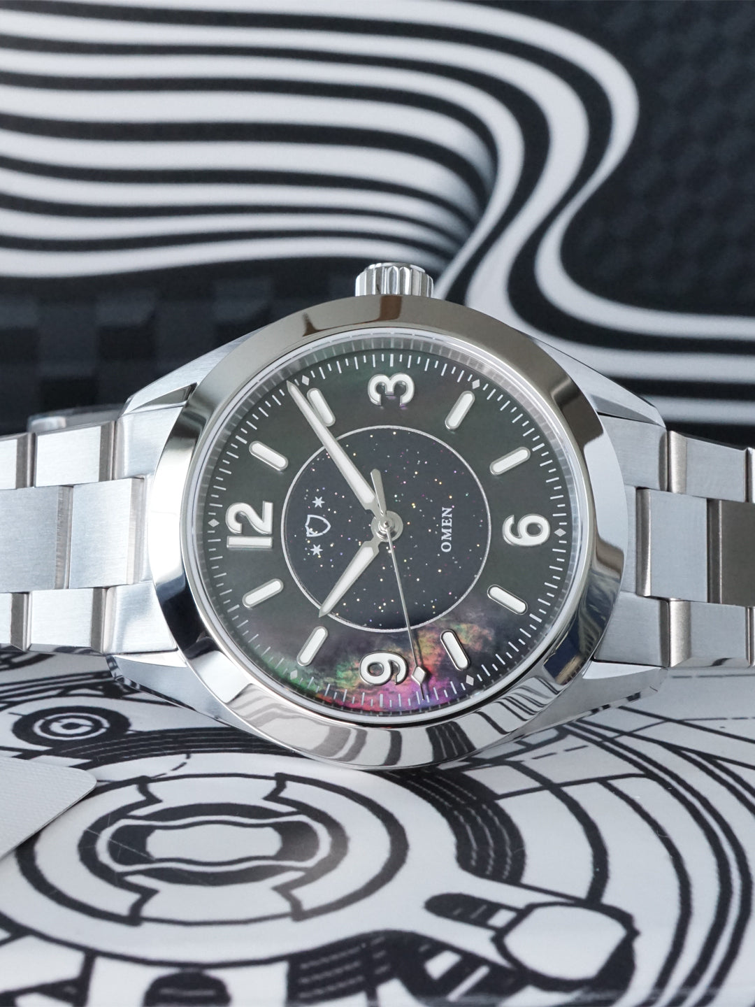 Silver wristwatch with a black dial on a black and white patterned background
