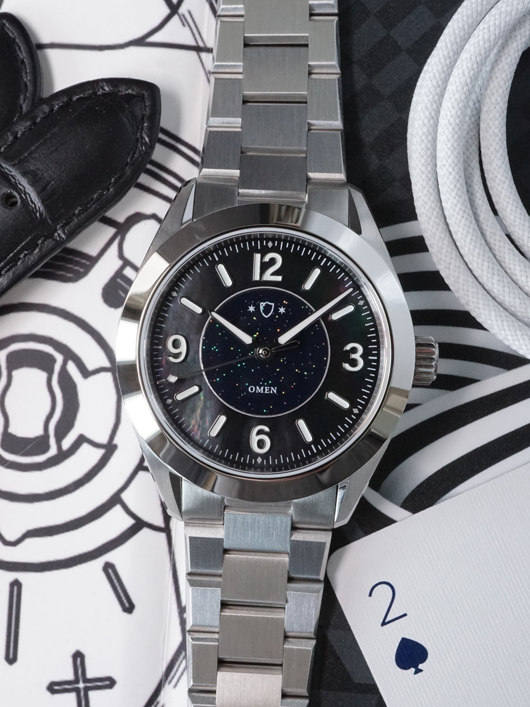 Silver watch with black dial on a patterned surface