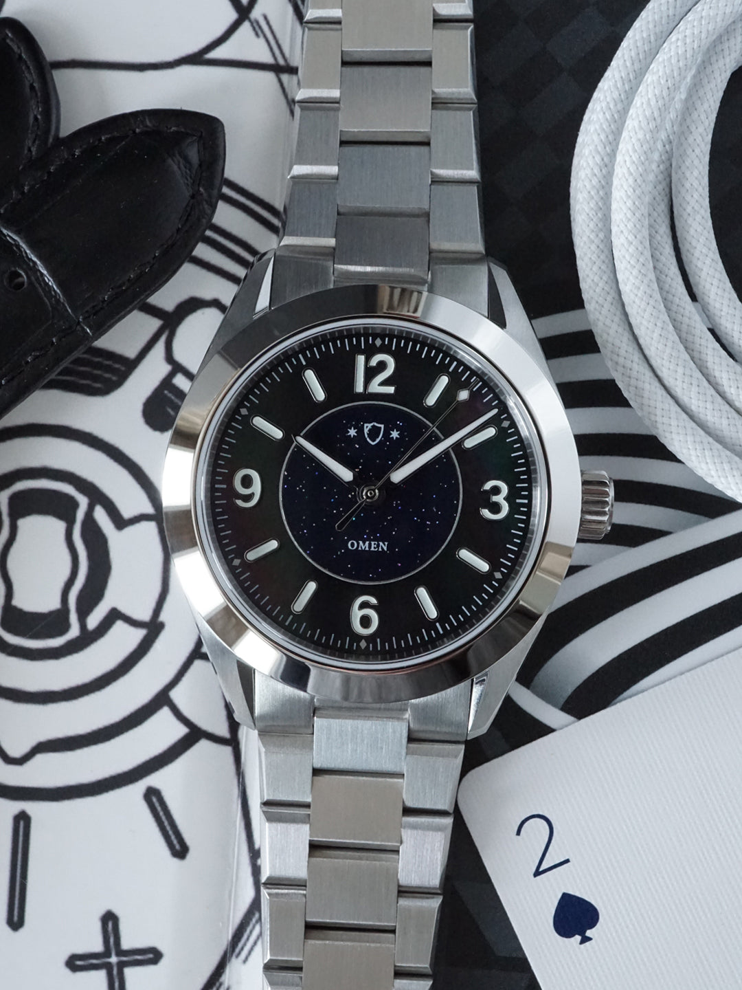 Silver watch with black dial on a patterned surface