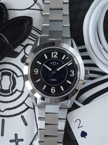 Silver watch with black dial on a patterned surface