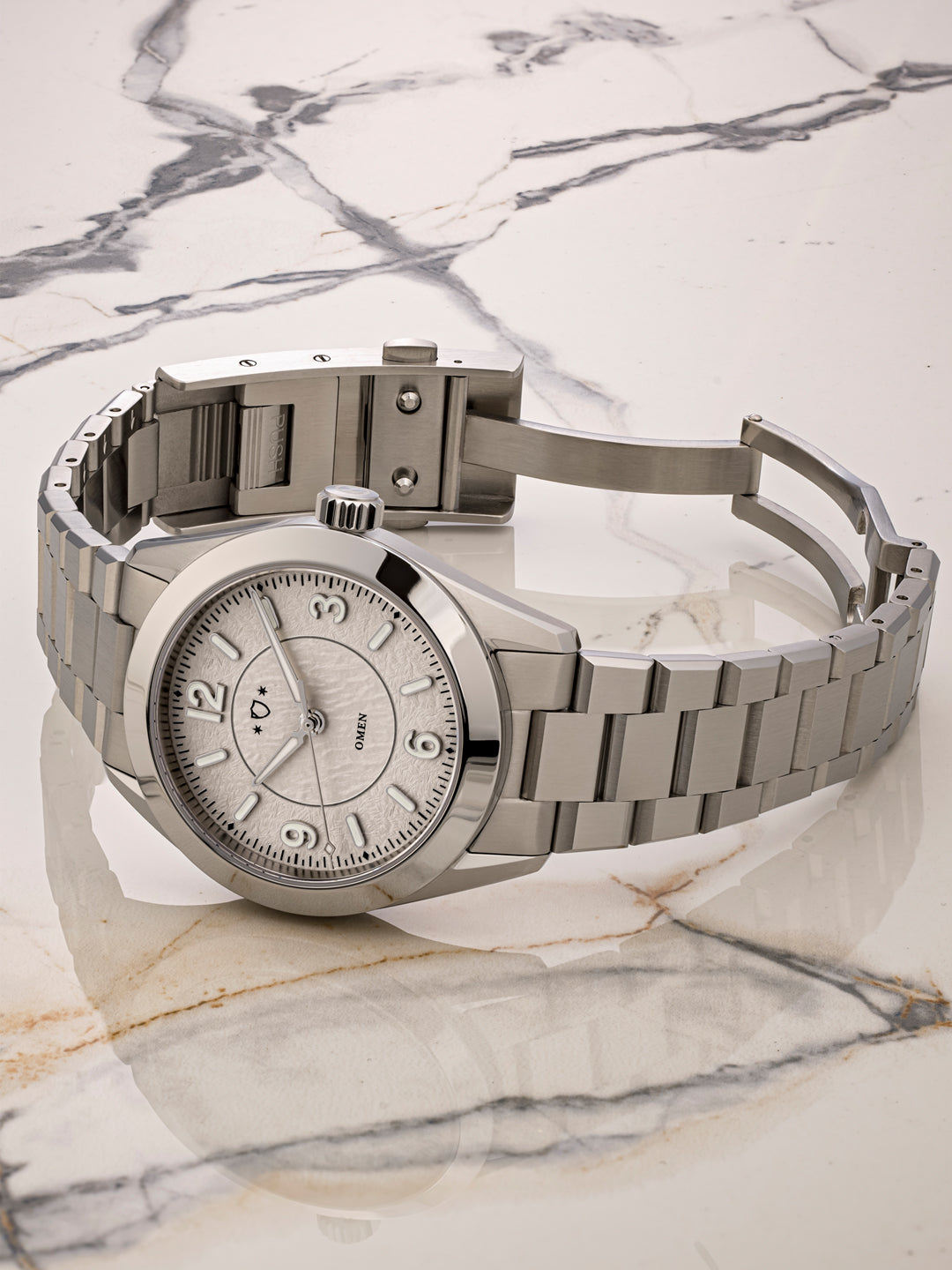 Silver watch with a metal band on a marble surface